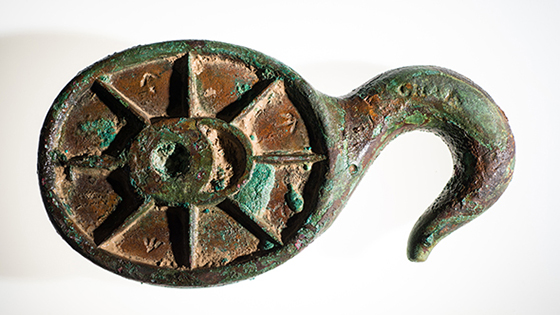 Among the artifacts recovered are a number of pieces of Erebus’ equipment and rigging, including fragments of the ship’s wheel, illuminators that allowed light into the lower decks, and rigging blocks and belaying pins to handle the masses of hemp ropes on such sailing vessels. This solid copper-alloy hook block, marked with several British broad arrows and “6 1/4” referring to its size, may have been used to lower one of the ship’s smaller boats or formed parts of its standard rigging. (Parks Canada)