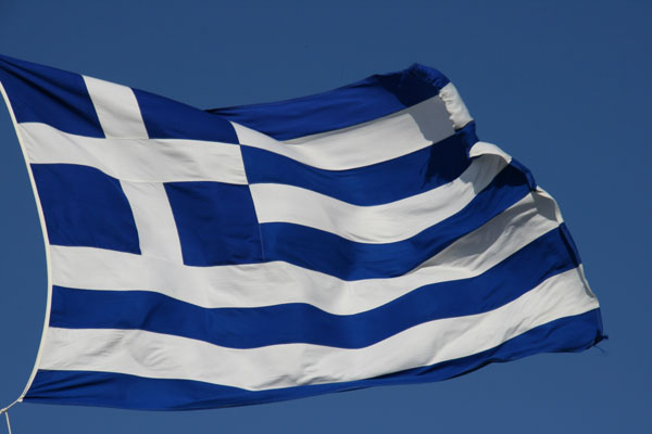 The familiar blue-and-white striped Greek flag flutters on the Acropolis.