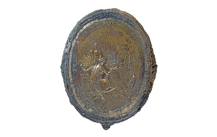 A brass-and-gold box for holding face powder decorated with an image of a reclining woman is one of the opulent artifacts recovered from the wreck that may have belonged to an affluent woman who is thought to have owned many of the ship’s other expensive objects.