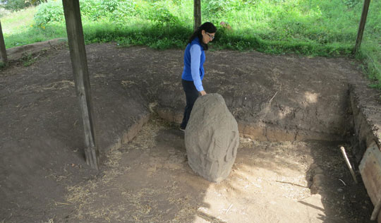 Bárbara Arroyo, lead archaeologist at Kaminaljuyú, inspects a ceremonial stone marker known as a stele. Carved with human and animal forms reflecting shifting artistic tastes, the volcanic boulder seems to have been worked and reworked over centuries. (Roger Atwood)