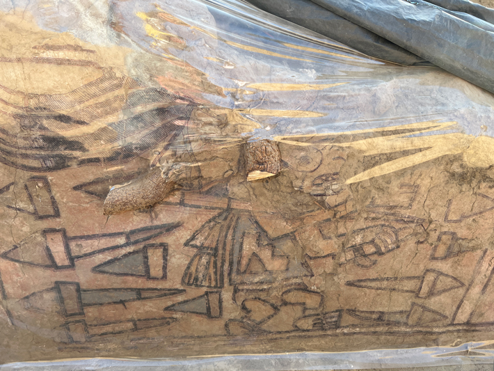 Archaeologists covered the newly discovered mural with plastic to preserve it and to enable them to trace the depictions of a warrior surrounded by geometric shapes.