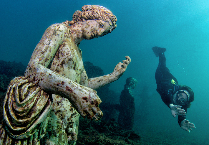 A diver swims by a replica of a statue of Dionysus, the god of wine, in the nymphaeum at Baiae. (Pasquale Vassallo)