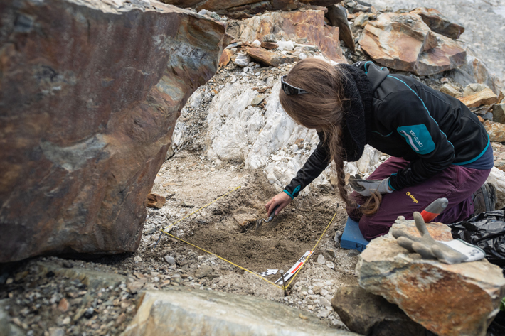 An archaeologist excavates at a site in the Swiss Alps where Mesolithic tools were found nearby a quartz vein (visible in the background), which was discovered by amateur geologist Heinz Infanger. (Valentin Luthiger/Institut Kulturen der Alpen)